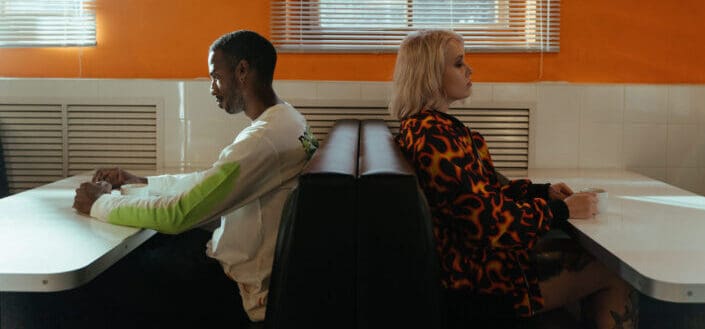 Two people sitting back to back to each other in a couch at a restaurant