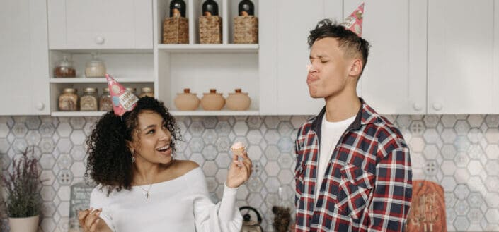 Couple wearing party hat while playing with the icing cake