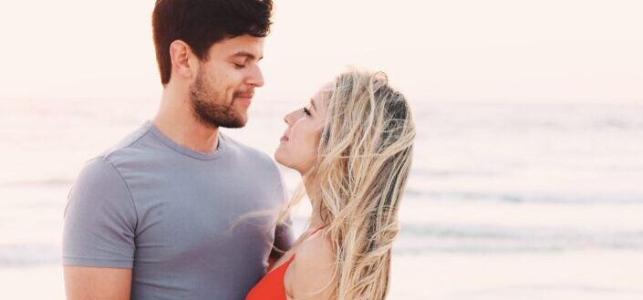 A man and woman looking at each other while on a beach