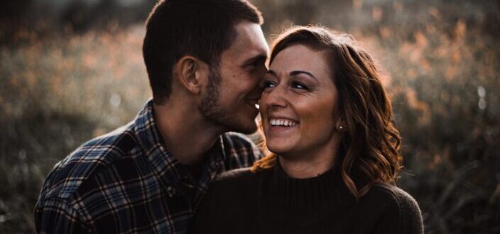 Man whispering something funny to her ear