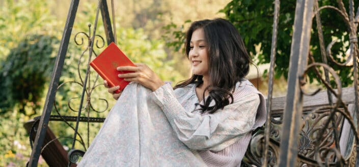 Woman sitting on a swing reading a Book 