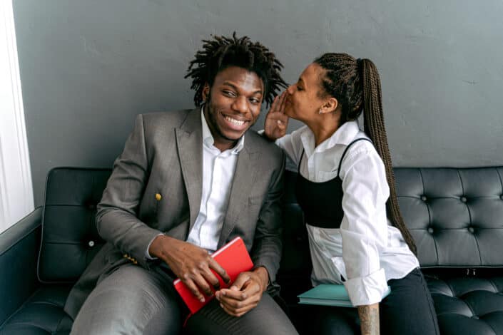 A woman whispering to the man's ear.