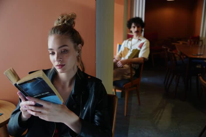 Woman in Black Leather Jacket Holding Blue Book