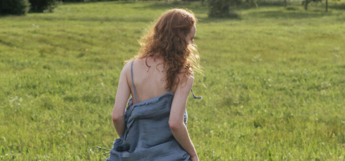 Woman in blue dress running on grass