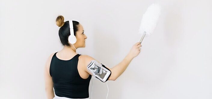 Hispanic cleaning lady dusts the wall.