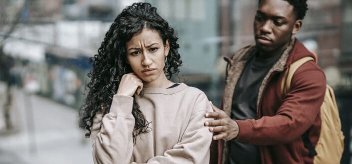 Man holding woman's shoulder looking sad