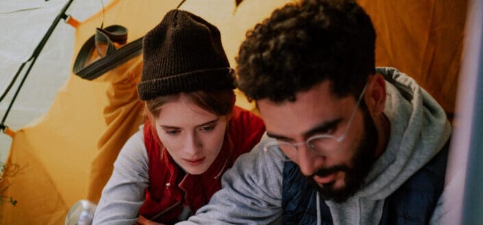 Man and woman looking at something while in a tent