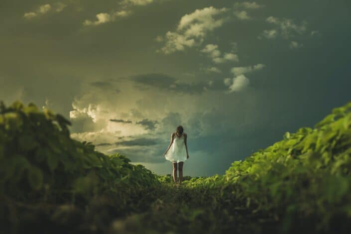 A woman standing on top of an island mountain alone.