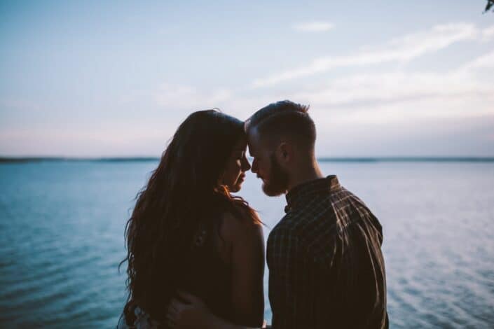 Couple about to kiss beneath the seaside.