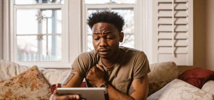 Man emotionally reading a message from his tablet.
