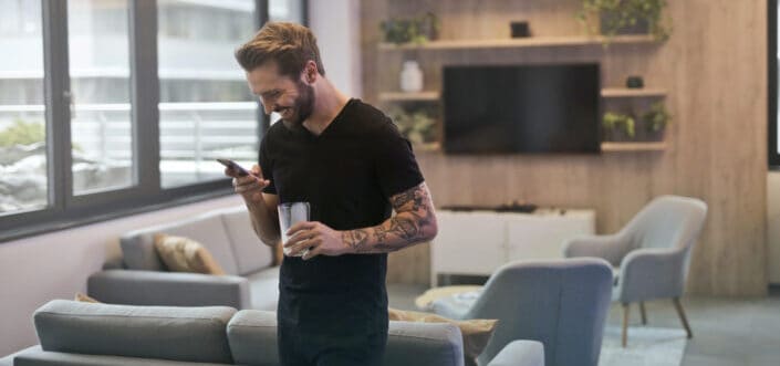 Man smiling while reading a message on his phone.