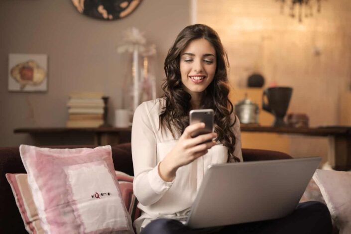 Woman delightfully reading a message from her phone.
