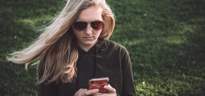 Woman in sun glasses chilling while texting.