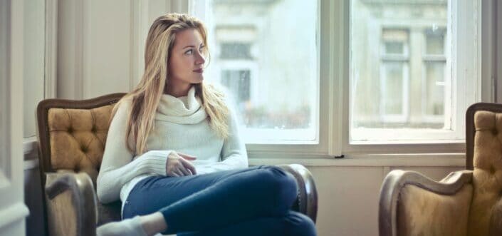Woman sitting while thinking and looking outside.