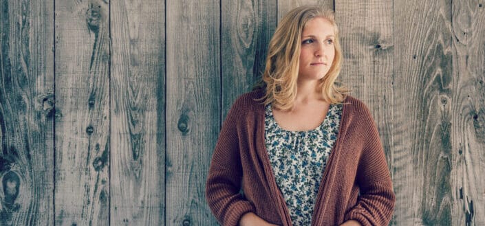 Woman Leaning Against Wooden Wall Looking Away