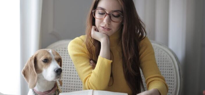 Woman reading a book beside her dog