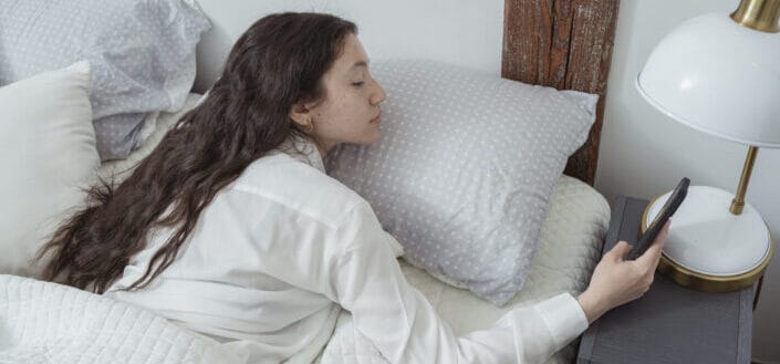 calm-female-using-smartphone-while-lying-on-bed-stockpack-pexels