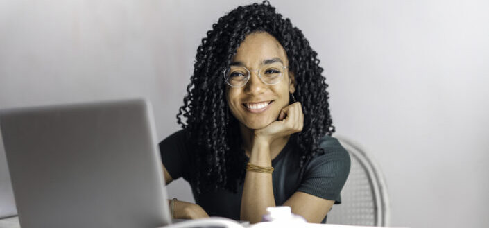 happy-ethnic-woman-sitting-at-table-with-laptop-stockpack-pexels