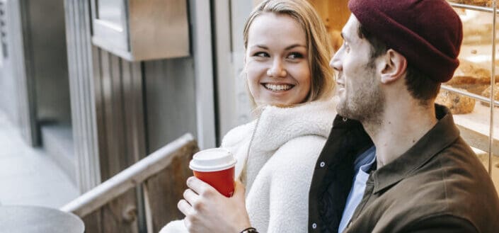 Positive young man and woman drinking coffee in coffee shop