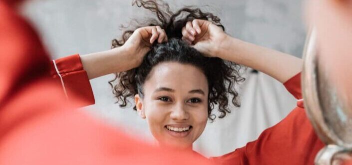 Curly Haired Woman Tying Her Hair in a Ponytail