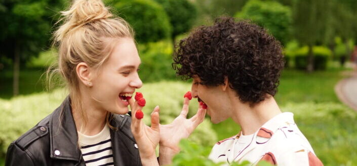 A playful couple eating raspberries