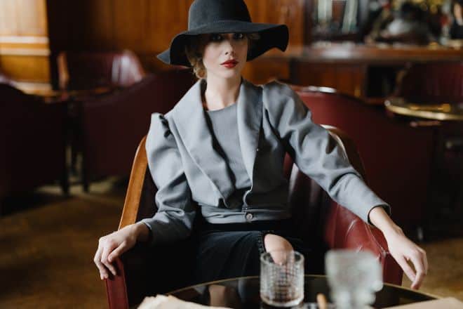 Woman in gray long sleeve blouse sitting on leather sofa chair - how to look expensive - main