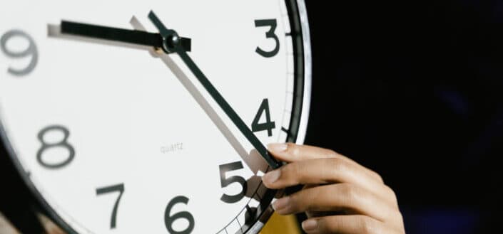 Person holding white analog clock