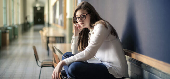 woman-in-white-long-sleeve-shirt-and-blue-denim-jeans-sitting-on-table-stockpack-pexels