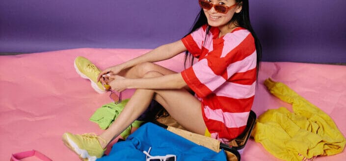 Woman sitting next to suitcase with clothes