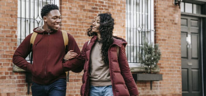 happy couple walking on street near building