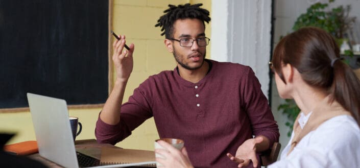 Man Holding Pen While Talking to a Colleague 