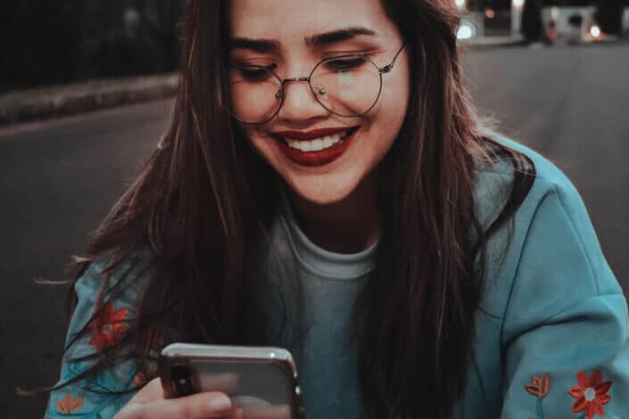 A woman smiling while sending text message on her phone