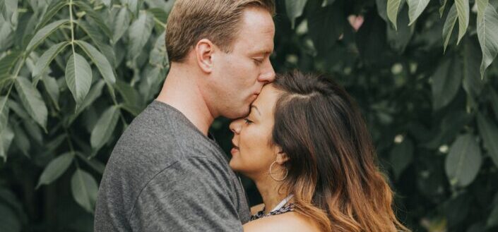 a man kissing his girlfriend on the forehead