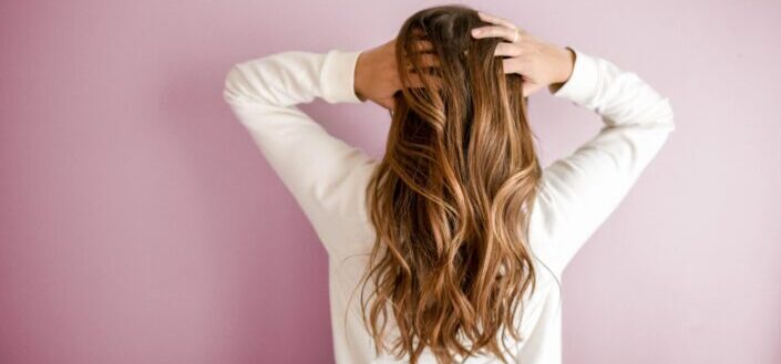woman messing her brown wavy hair