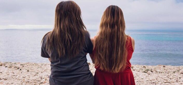 2 Women Sitting on the Beach During Daytime