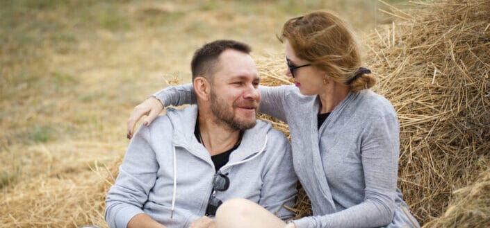 a couple sitting on a wheat field