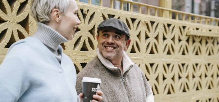 Content couple with coffee to go speaking on urban street