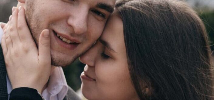 Crop smiling couple embracing on street in daytime