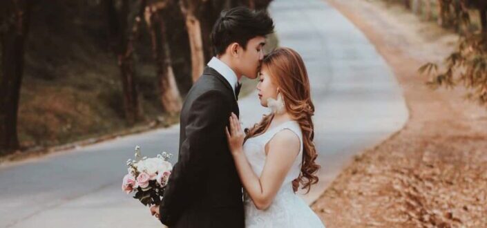 Groom kissing elegant bride on road
