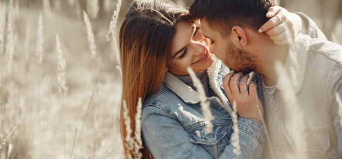 Loving young couple hugging on dry grass in field in countryside