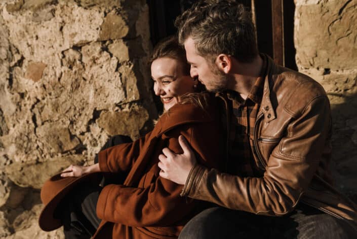 Man and woman sitting in the stairs behind a stone building