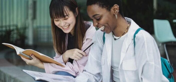 Female Students With Workbooks Talking Outside