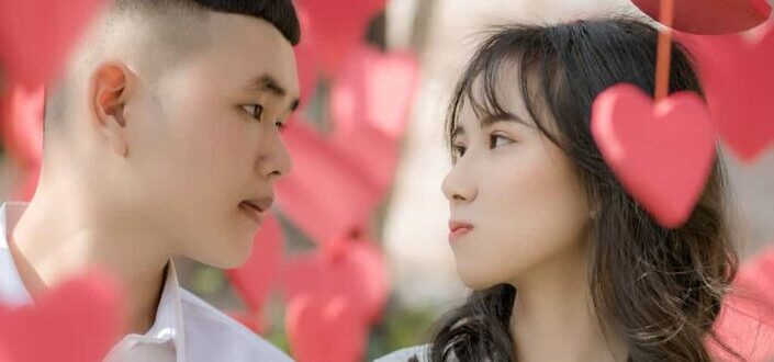 Newlywed young asian couple amidst hanging decorative hearts