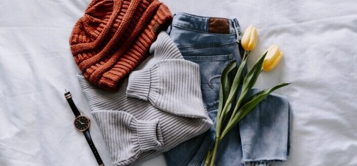 Orange Knit Cap and Gray Sweater With Yellow Tulips Laid Out on the Bed