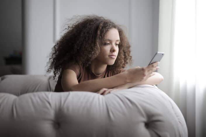 Woman sitting on a gray bean bag while using her phone