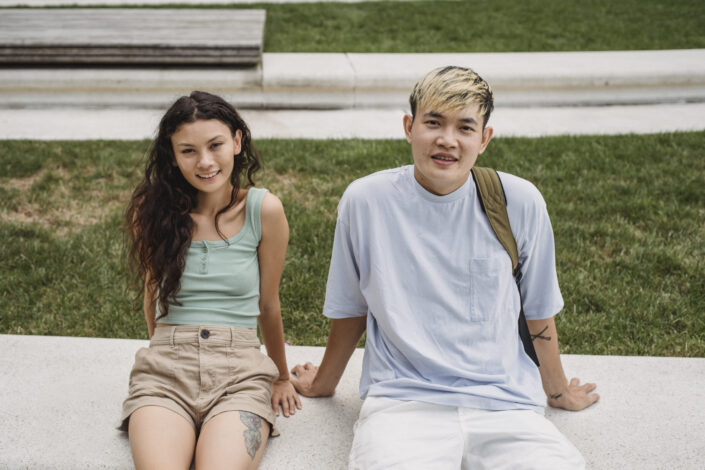 Smiling multiethnic couple resting on street bench in town