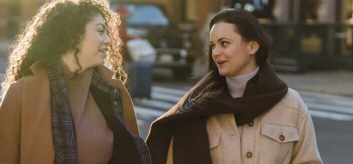 Stylish Young Women Chatting While Strolling in City