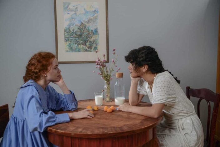 Women Looking at Each Other While Sitting on a Chair