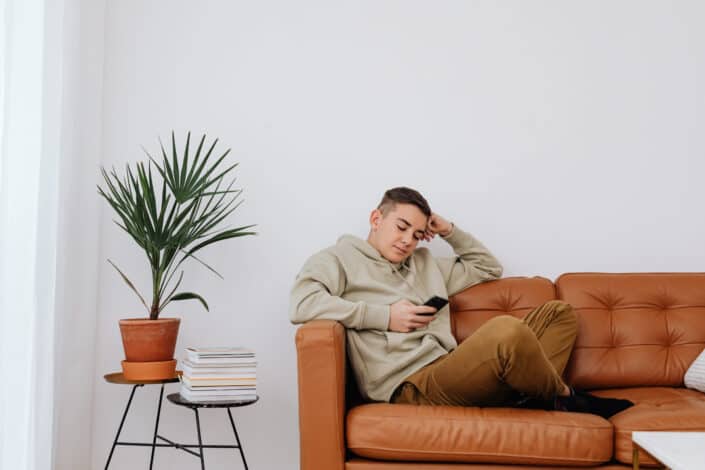 A man in brown hoodie sweater holding a cellphone