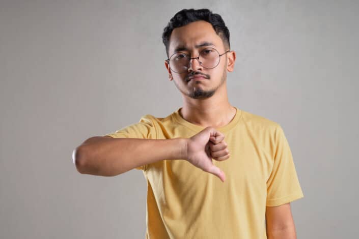 A man wearing eyeglasses doing thumbs down